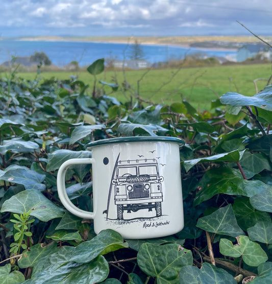 Land Rover front view with surfboard on beach enamel mug
