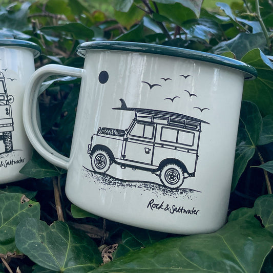 Land Rover side view with surfboard on beach enamel mug